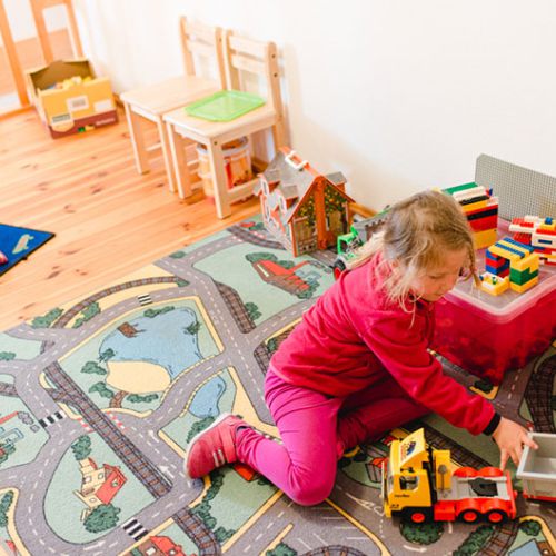 Mädchen spielt im Kinderzimmer mit einem Traktor
