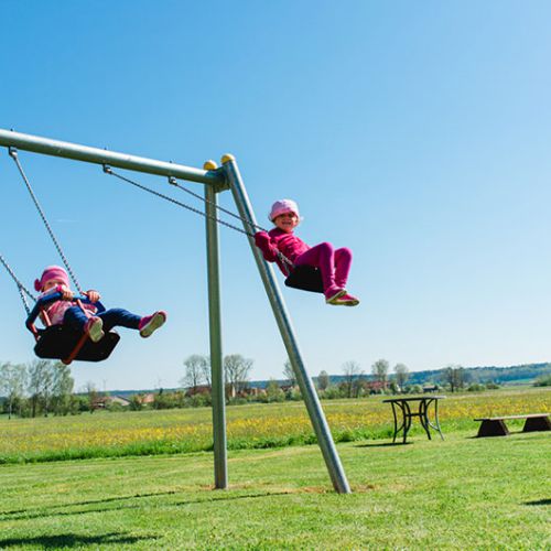 Kinder schaukeln auf der Wiese